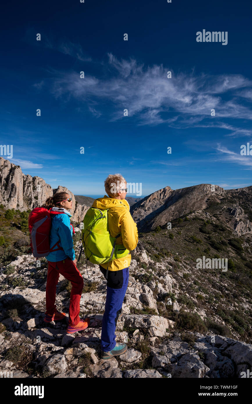 Two women on a hike looking towards the valley, hiking in Sierra de Serrella, Quatretondeta-Confrides, Alicante province, Comunidad Valenciana region, Stock Photo