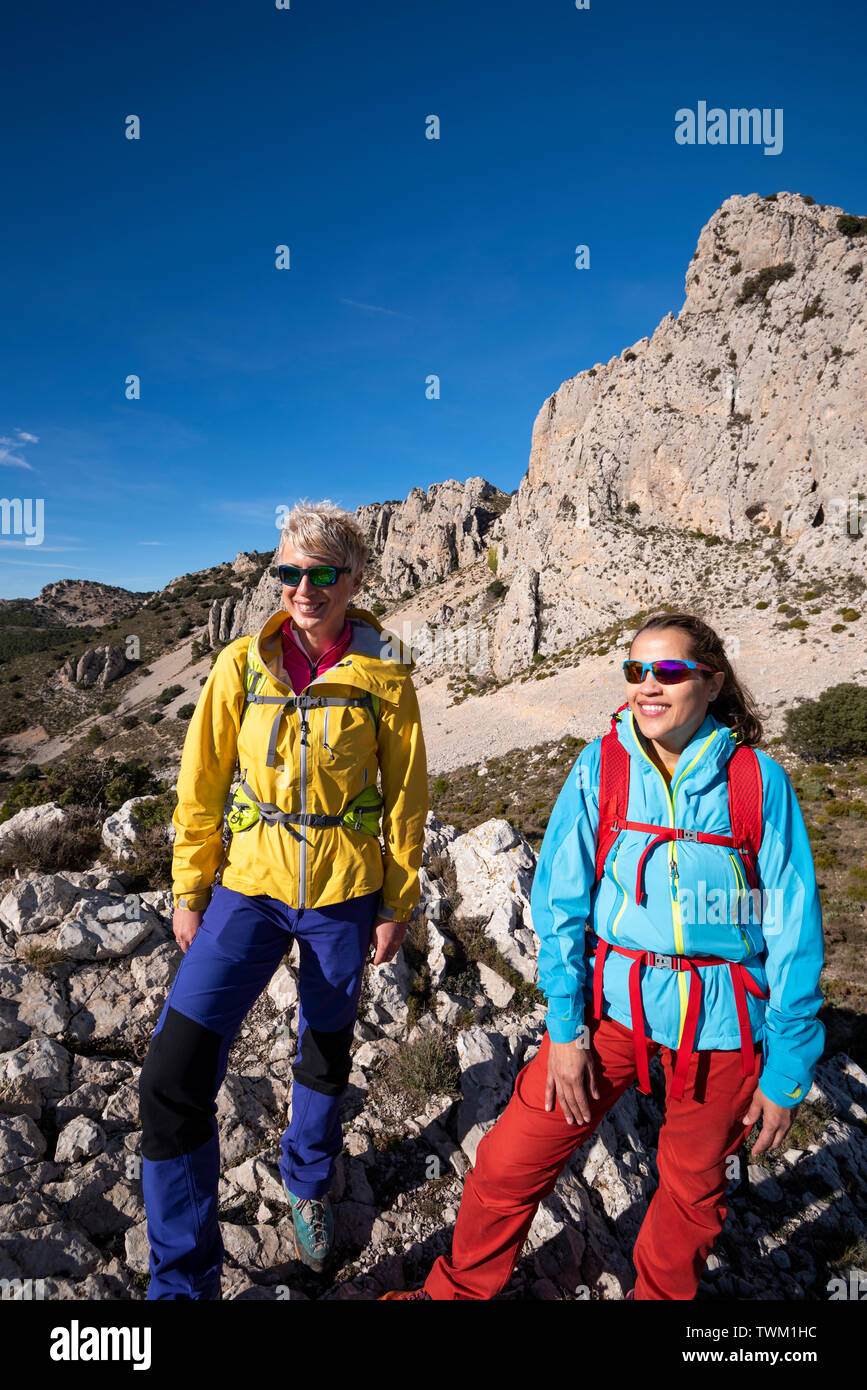 Two women on a hike looking towards the valley, hiking in Sierra de Serrella, Quatretondeta-Confrides, Alicante province, Comunidad Valenciana region, Stock Photo