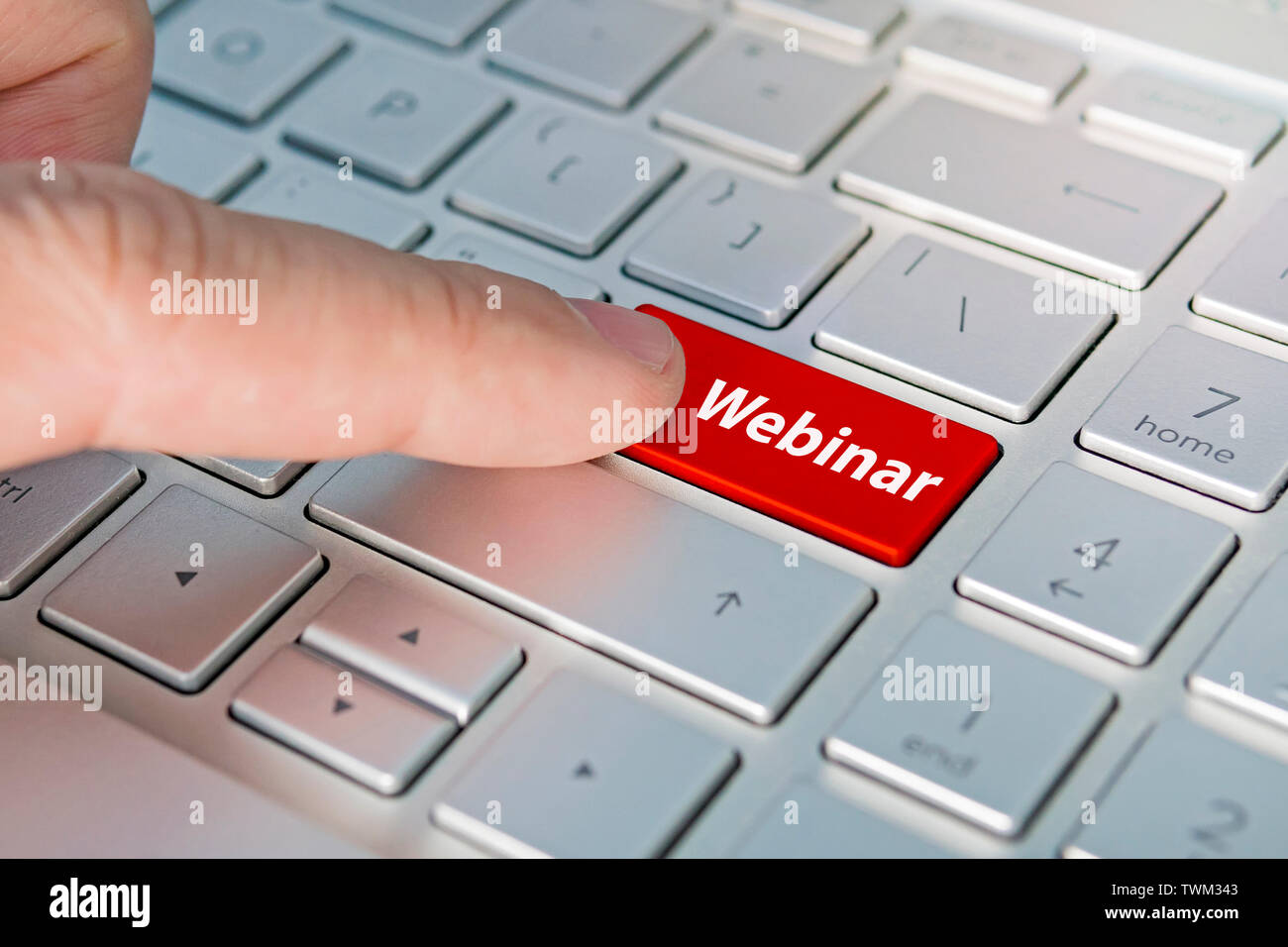 Webinar, Computer keyboard with webinar button concept. A male finger presses a color button on a gray silver keyboard of a modern laptop. Button with Stock Photo