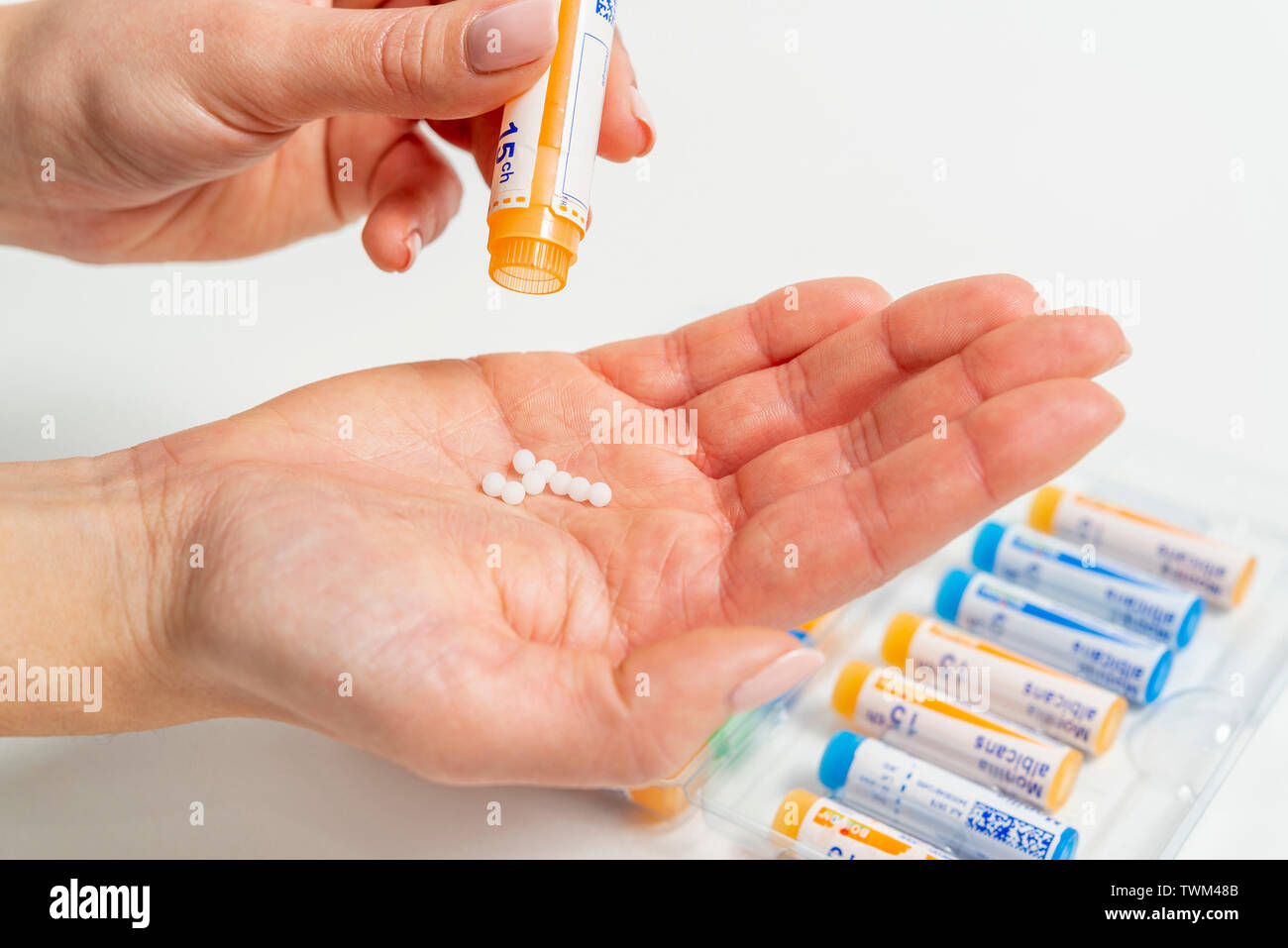 Homeopathic tubes: homeopathic granules, tubes from the Boiron laboratories. Woman putting homeopathic granules in her hand Stock Photo