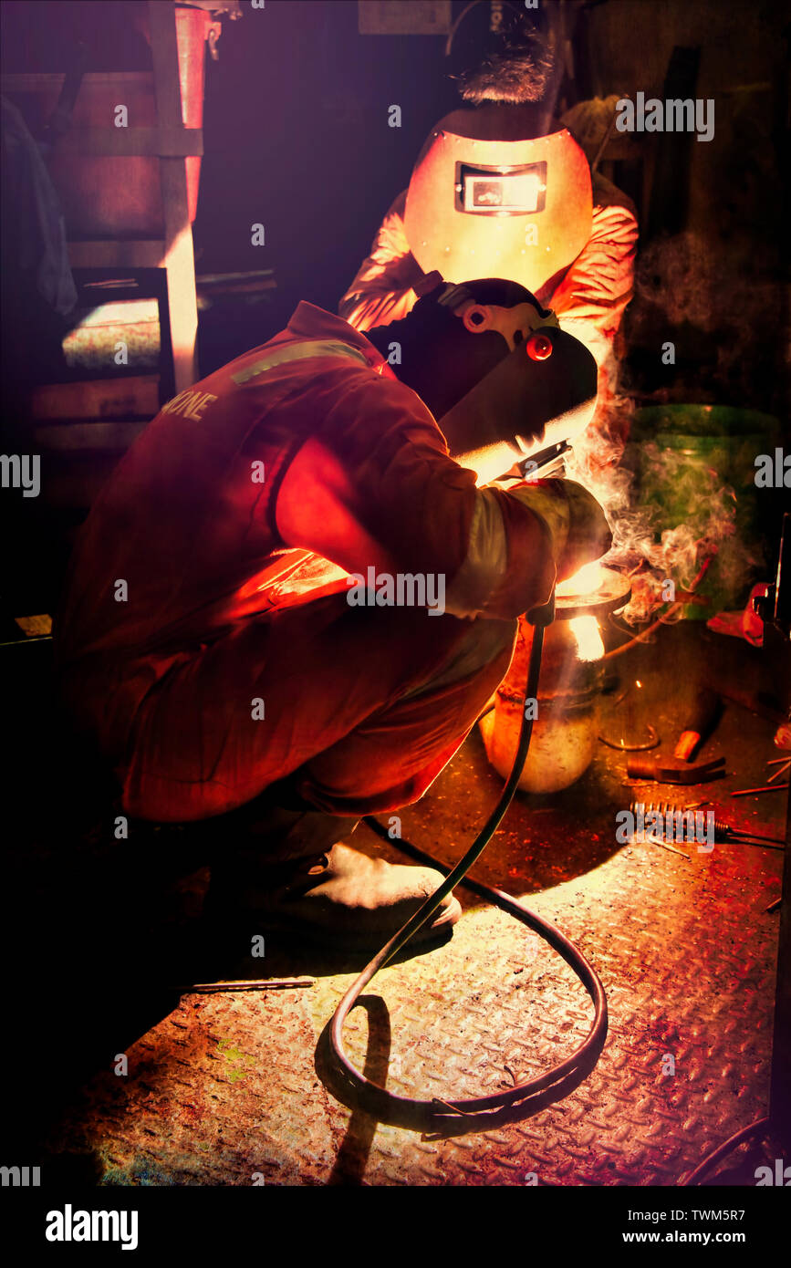 marine crew welding leaked pipe in engine room workshop Stock Photo