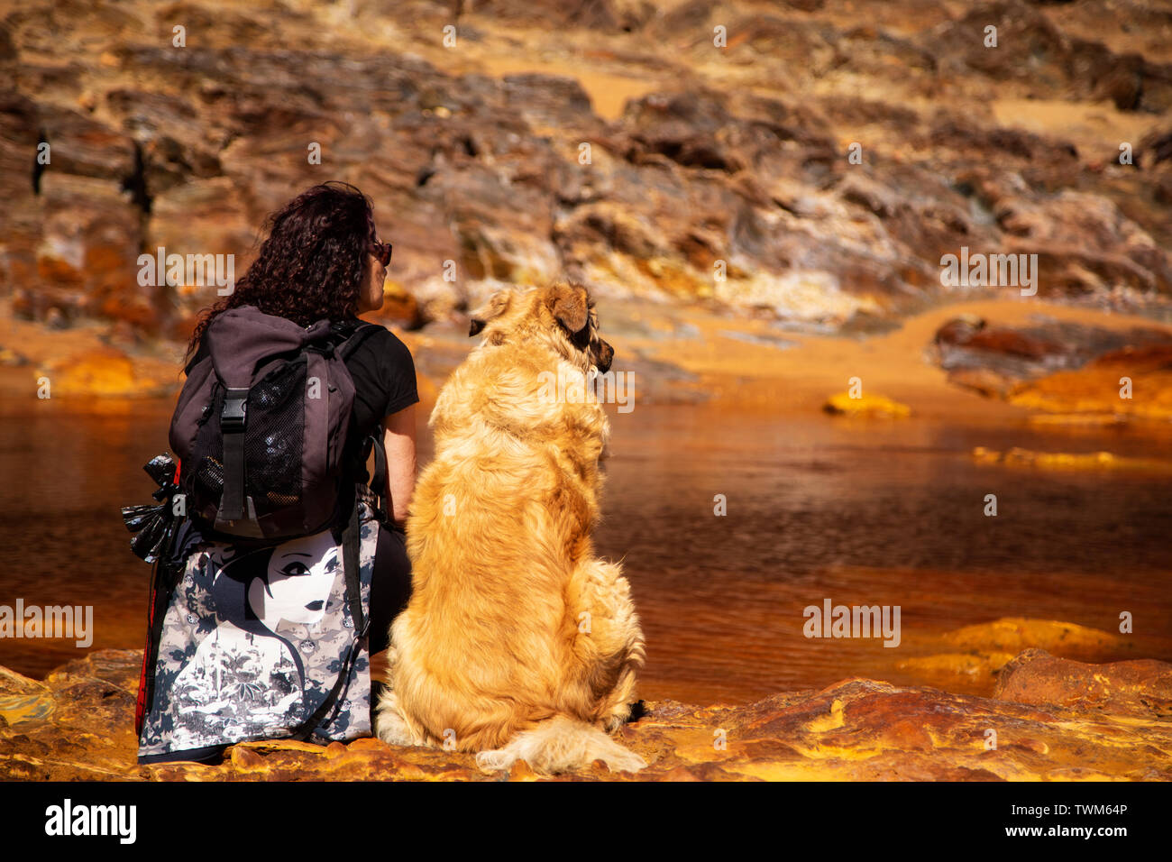 Woman sitting in the edge of Rio Tinto with her dog Stock Photo