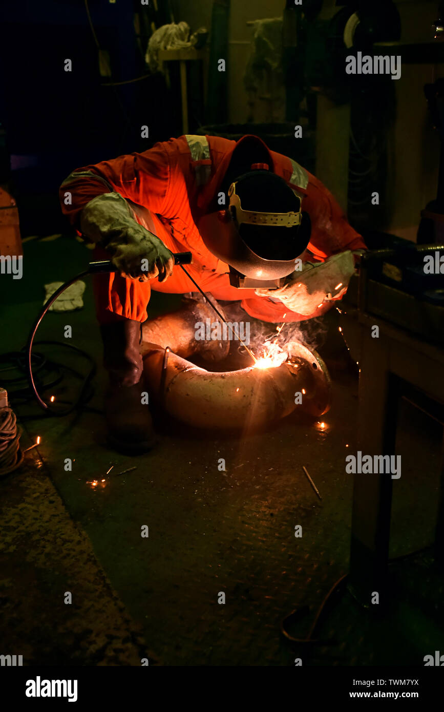 welder and his helper fabricate pipe in a wearing with