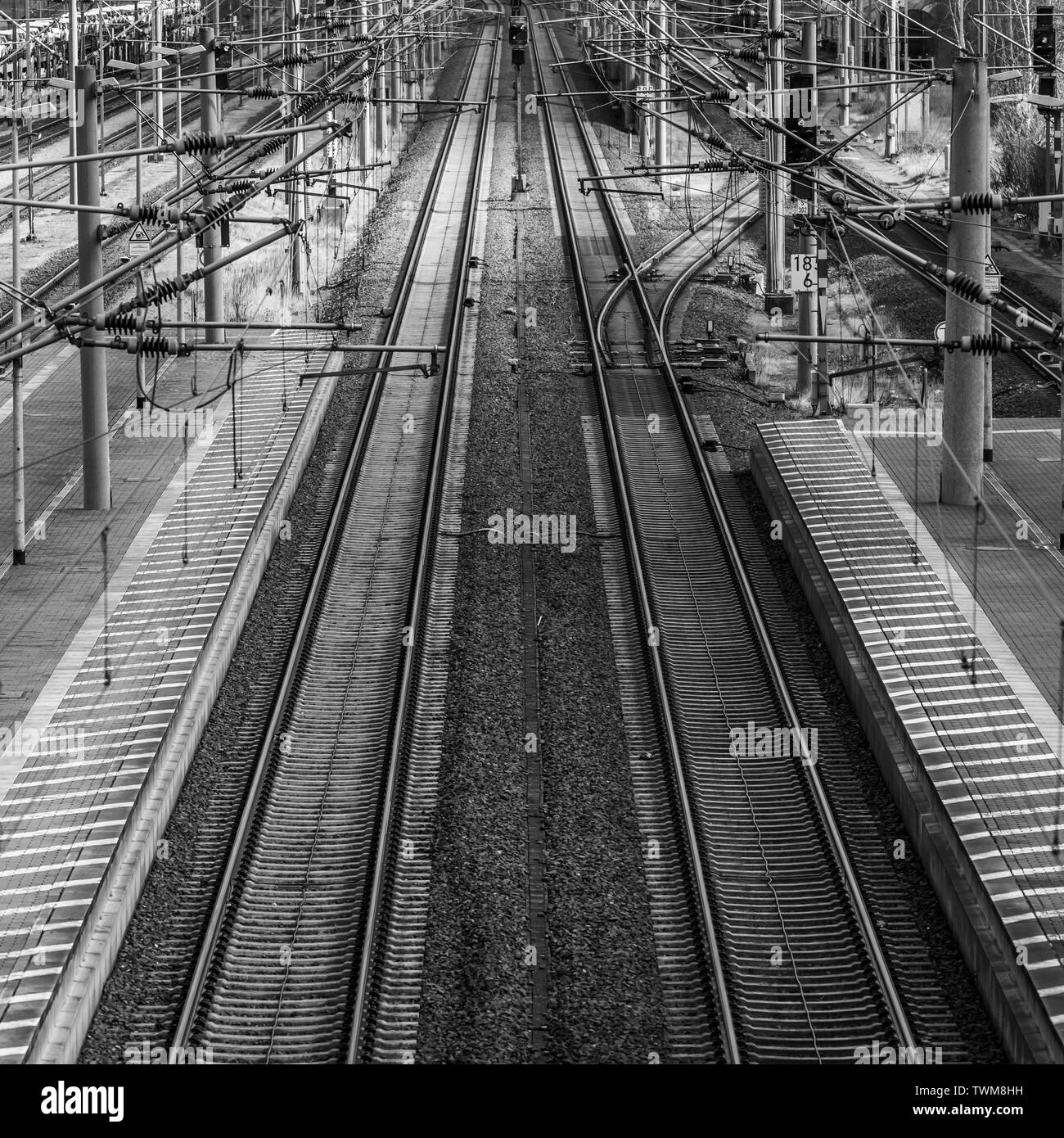 Perspective view of railway tracks with overhead lines next to a platform, monochrom Stock Photo