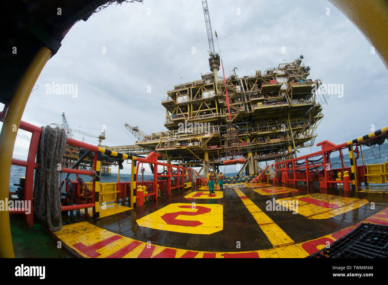 view distort oil platform during morning with two ship crew walking back to accommodation Stock Photo