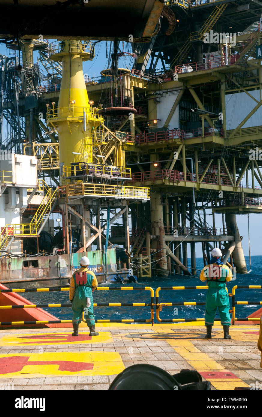 marine crew transferring oil platform personal from accommodation barge to vessel by crane using safety personal basket Stock Photo
