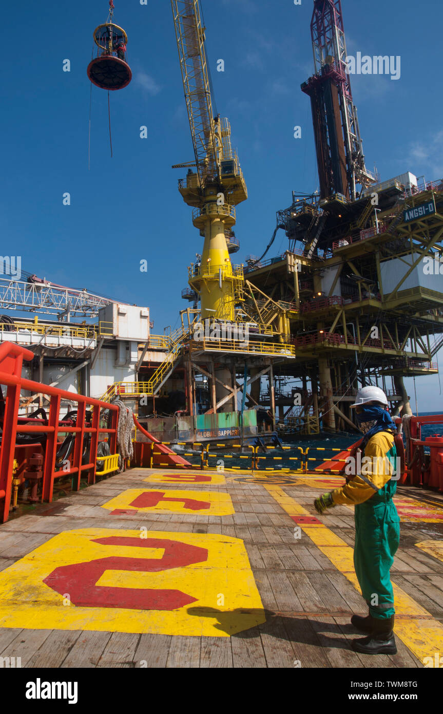 marine crew transferring oil platform personal from accommodation barge to vessel by crane using safety personal basket Stock Photo