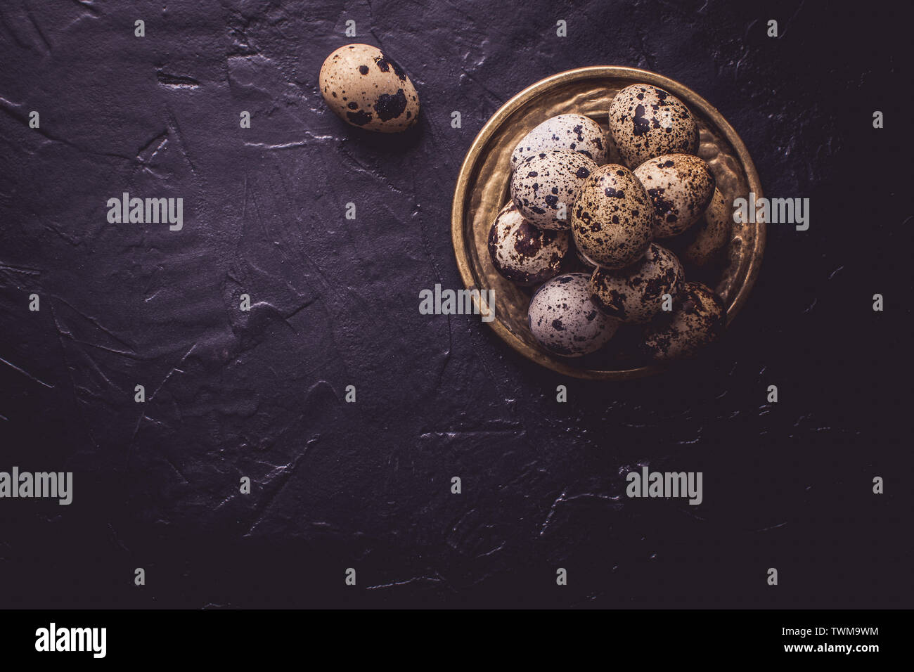 Small Quail Eggs on Dark Stone Background Stock Photo