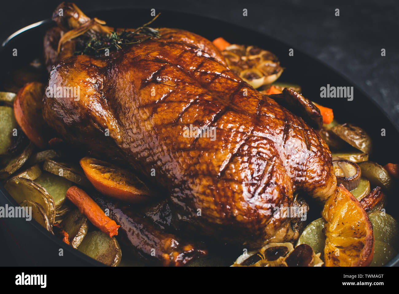 Roasted Whole Goose with Carrots, Oranges and Potatoes on Dark Stone Background Stock Photo