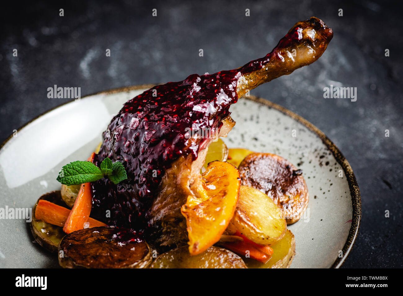 Roasted Fat Goose Leg with Potatoes, Carrots and Oranges Stock Photo