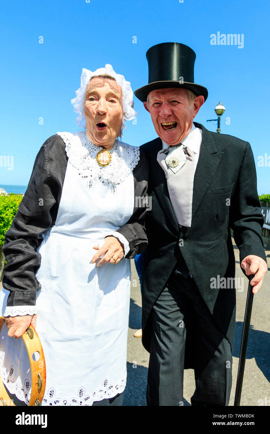 Broadstairs Dickens Festival. Outdoors, a senior woman house maid looking shocked and surprised as a senior gentlemen stands next to her and grabs her bottom in a little playful hanky panky. Stock Photo