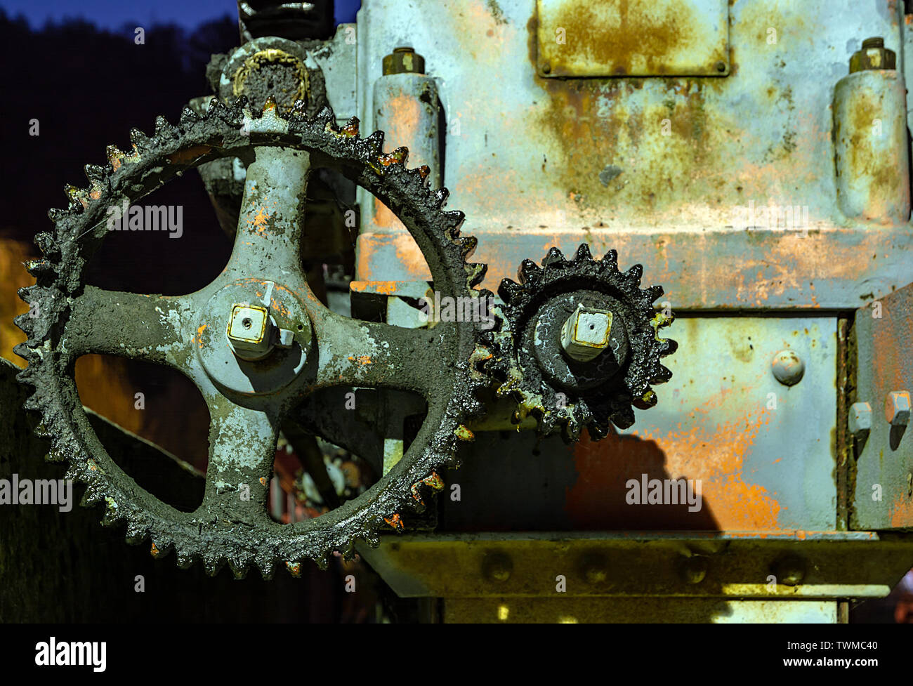Vintage oily and rusty illuminated cogwheel at night Stock Photo