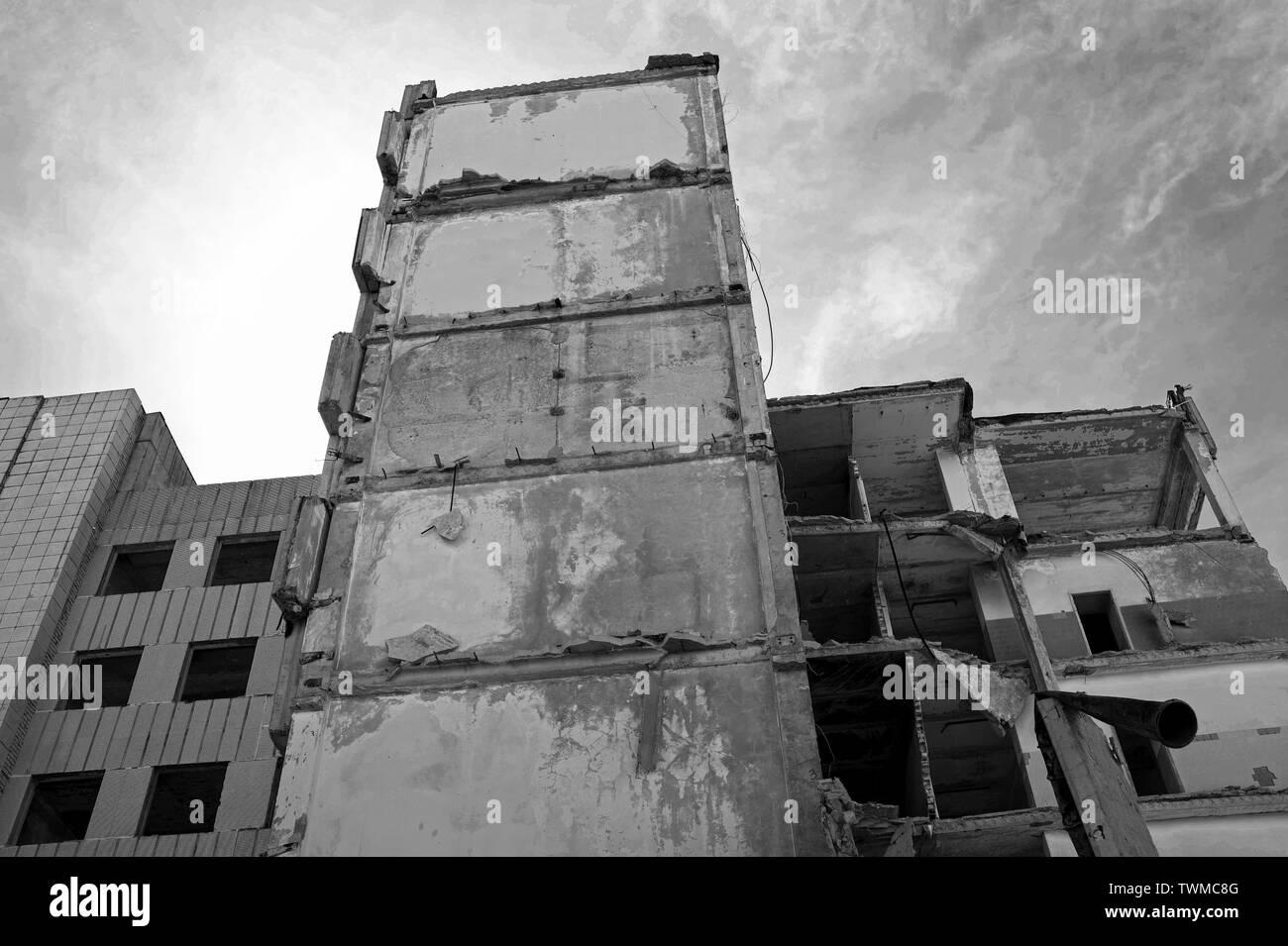 Destroyed large concrete building against the sky. Background. Bottom view. Black and white