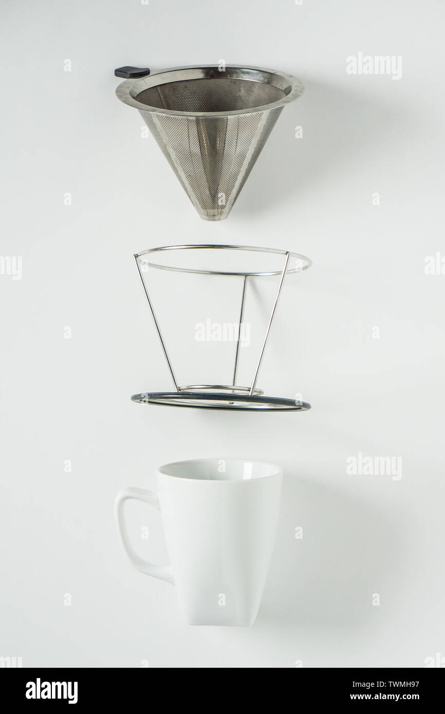 White coffee mug on white background with filterless metal pour over drip cone pulled apart with
