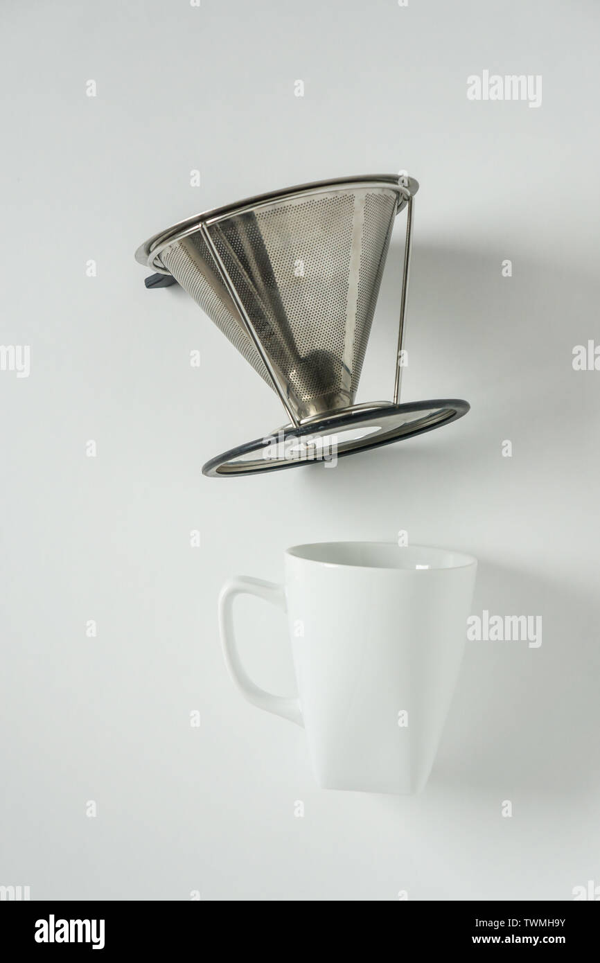 White coffee mug on white background with filterless metal pour over drip cone with blank empty