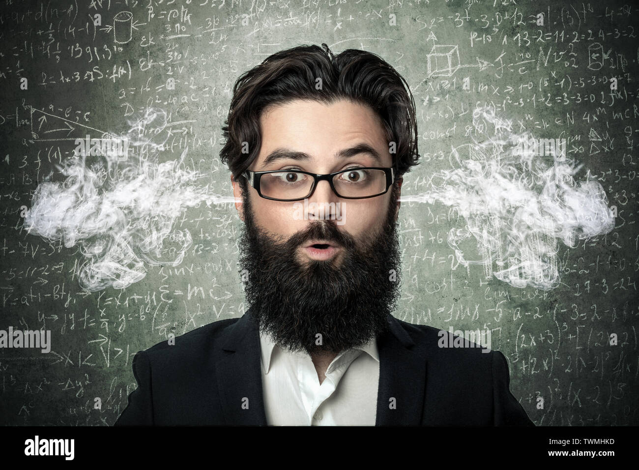 bearded man with smoke coming out from his ears, over blackboard inscribed with scientific formulas and calculations in physics and mathematics, conce Stock Photo