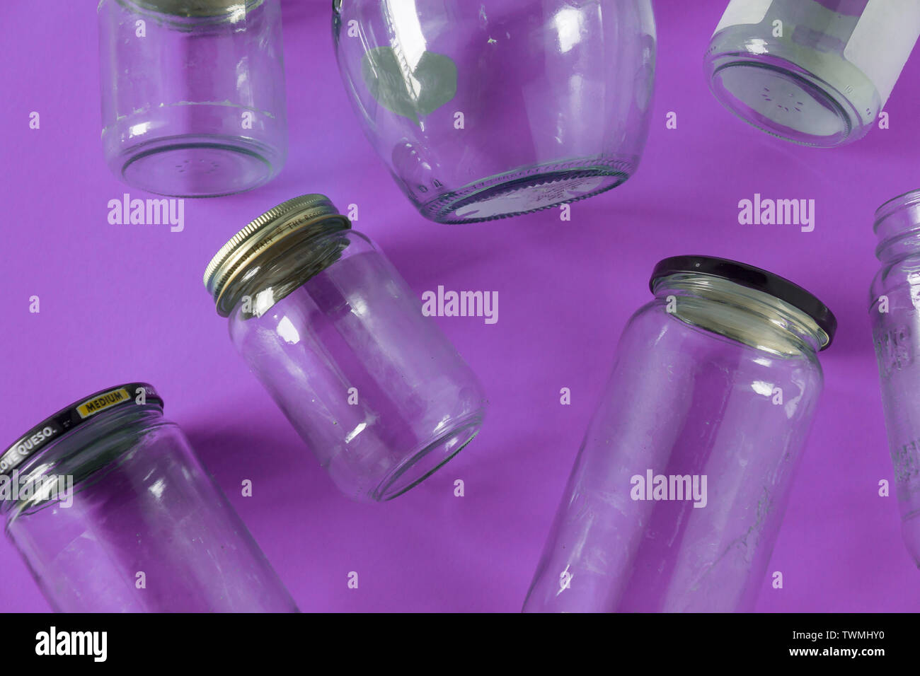 Transparent glass jars with lids isolated on purple background, top view flat lay recycling concept for environmental awareness. Segregated recyclable Stock Photo