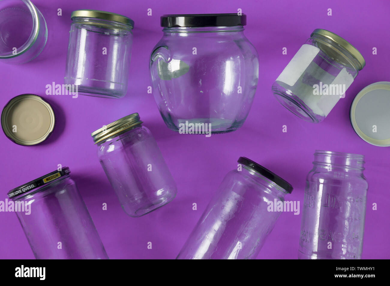 Transparent glass jars with lids isolated on purple background, top