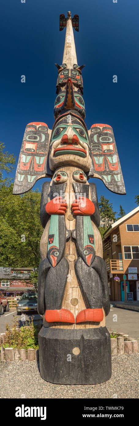 Sept. 17, 2018 - Ketchikan, AK: Tall panoramic of beautiful and very tall Chief Johnson Totem Pole with clear dark blue sky and local buildings. Stock Photo