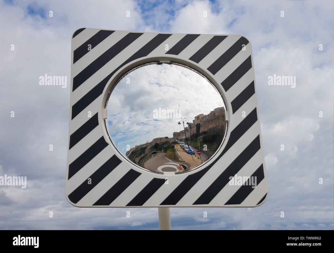Round road mirror against the cloudy sky. Stock Photo