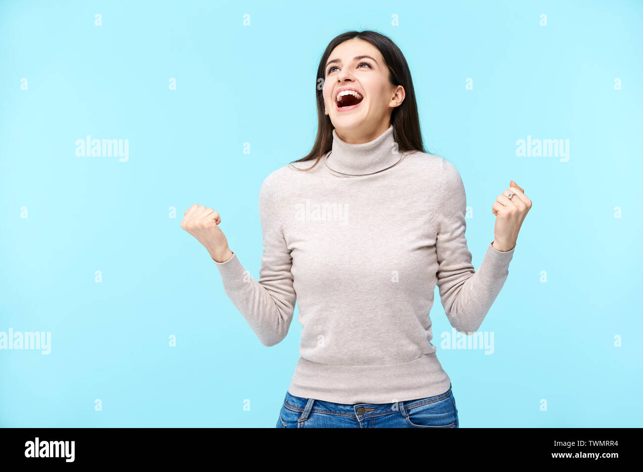 young caucasian woman making fists looking up shouting and screaming, isolated on blue background Stock Photo