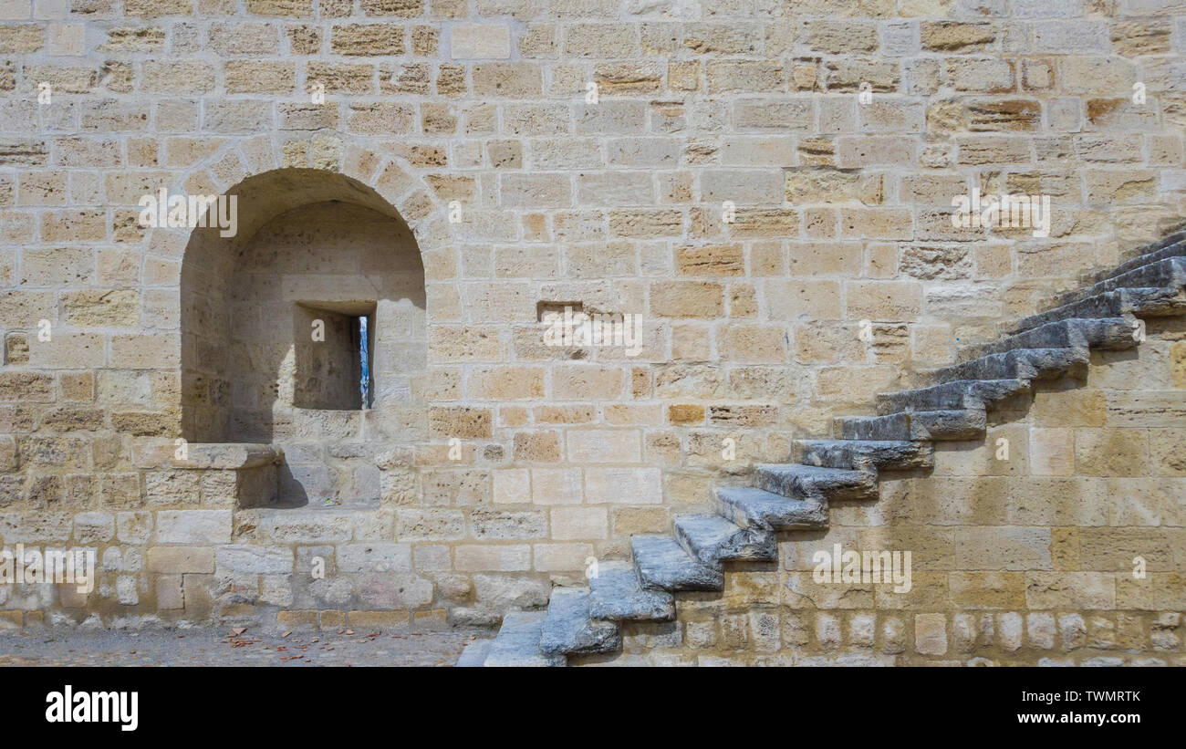 An embrasure and a staircase on the stone wall of an ancient fortress ...