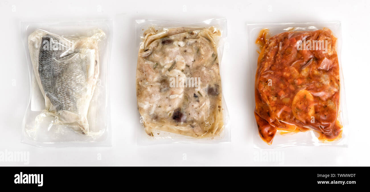 Three different fresh vacuum packed healthy meals in plastic air-tight wrapping with a fish fillet, rabbit and ossobucco arranged on a white backgroun Stock Photo