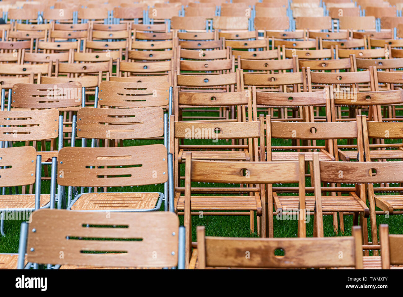 Wooden chairs closeup stand outside in the park in the rain. Empty