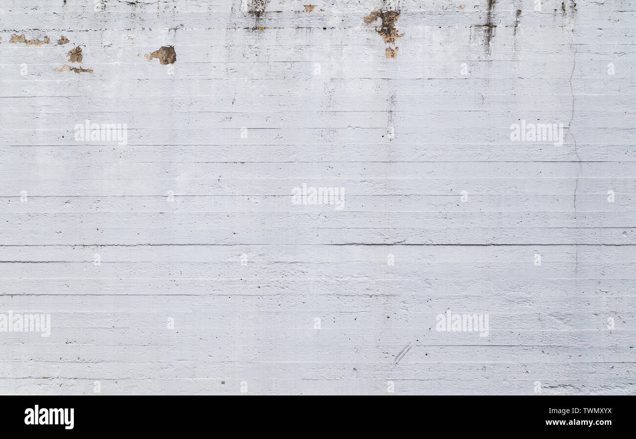 High resolution full frame texture background of a plastered, painted, uneven and a bit dirty white concrete wall. Paint is partly peeled off. Stock Photo