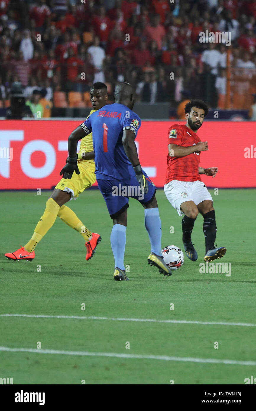 Cairo, Egypt. 21st June, 2019. Zimbabwe goalkeeper Edmore Sibanda (C) gets to the ball before Egypt's Mohamed Salah (R) during the 2019 Africa Cup of Nations Group A soccer match between Egypt and Zimbabwe at the Cairo International Stadium. Credit: Omar Zoheiry/dpa/Alamy Live News Stock Photo