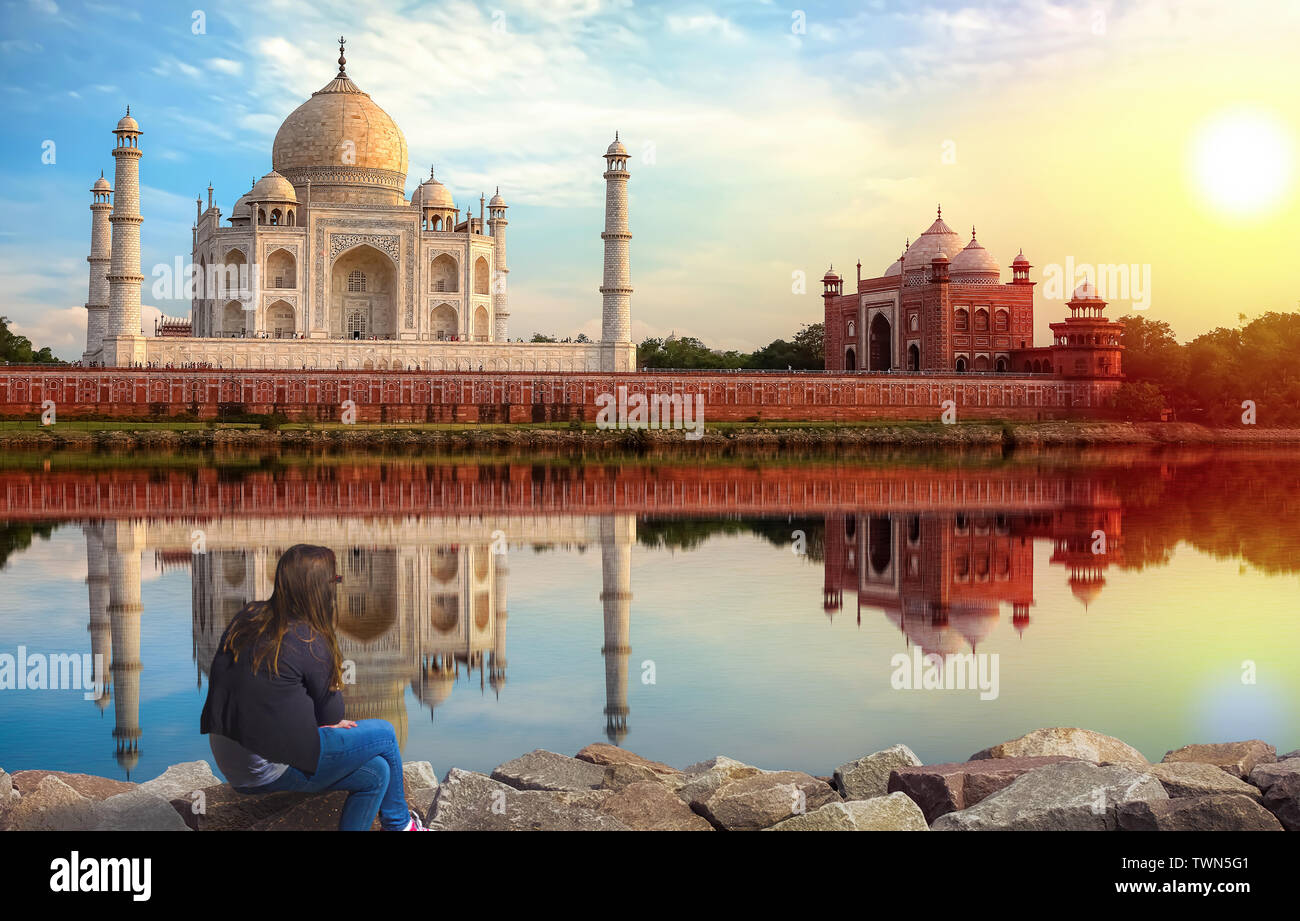 Taj Mahal Agra sunset view with young female tourist enjoying the view from Mehtab Bagh on the banks of river Yamuna Stock Photo