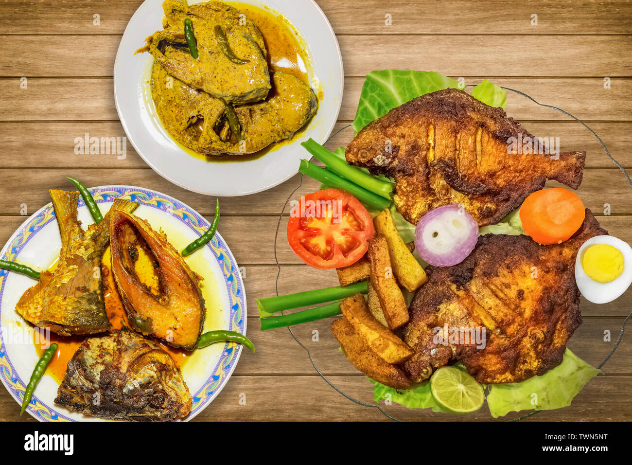 Indian fish food (cuisine) dishes on display comprising of deep fried pomfret fish with rohu fish and hilsa fish curry Stock Photo