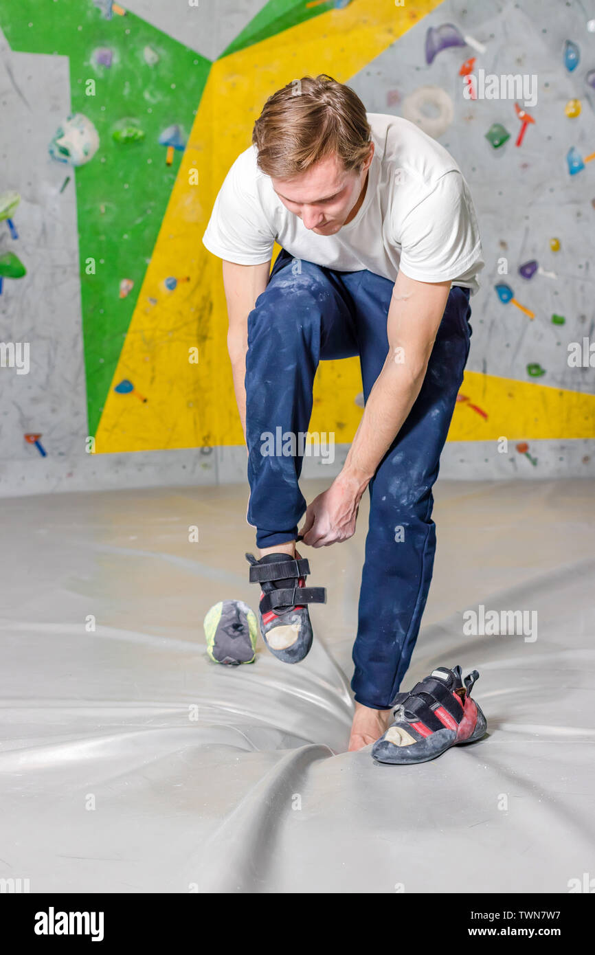 Rock climber puts on rocky shoes in a bouldering hall at a climbing gym