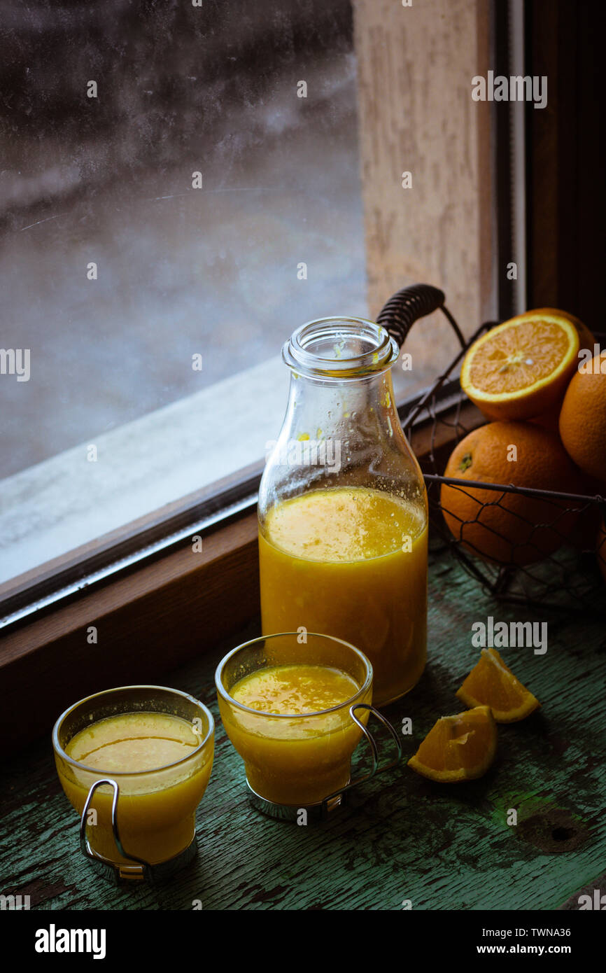 Bottle and glasses with orange juice. Moody. Stock Photo