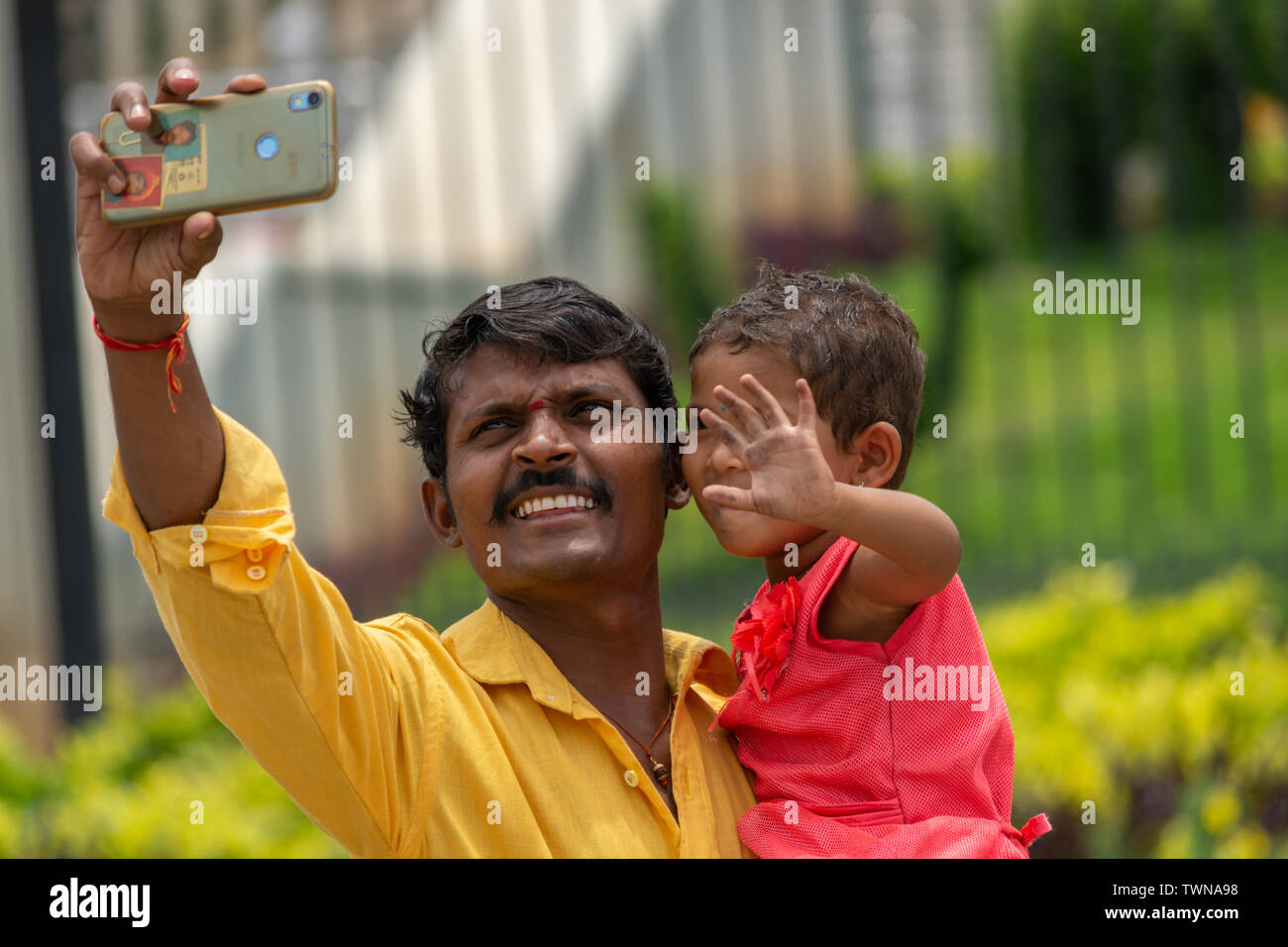 Bangalore, Karnataka India-June 04 2019 : Father and little cute daughter taking picture or selfie with Mobile Phone or cellphone camera at tourist pl Stock Photo