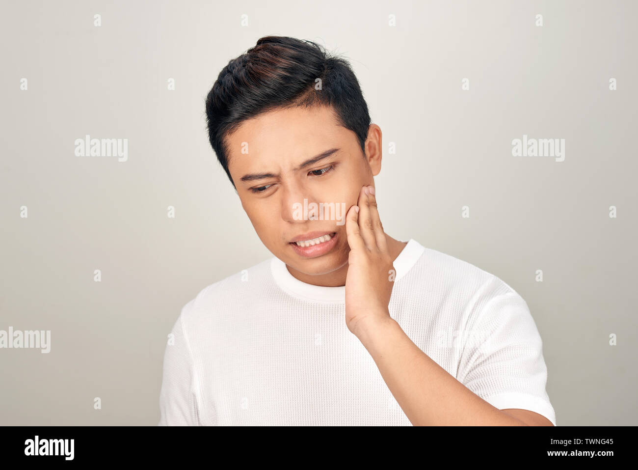 Portrait of fat Asian man use his hand touch his cheek, feeling painful from toothache. Oral health concept. Stock Photo