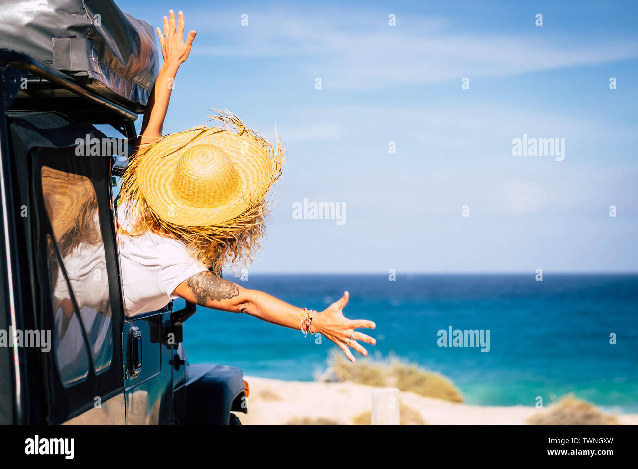 Travel and freedom concept with happiness and joy - people in summer holiday vacation - woman outside the car in front of a scenic beautiful beach and Stock Photo