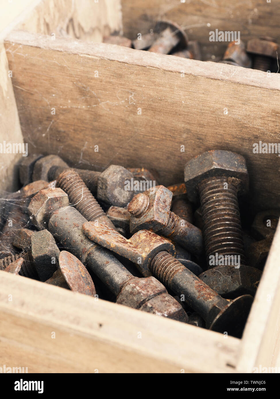 Rusty old nuts and bolts in a rustic wooden box on a workbench