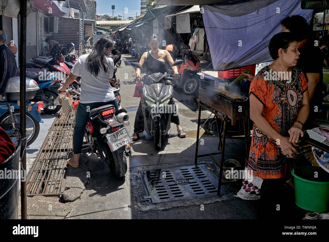 Congested street. Thailand side street with food vendor encroaching and impeding motorcycle traffic Stock Photo