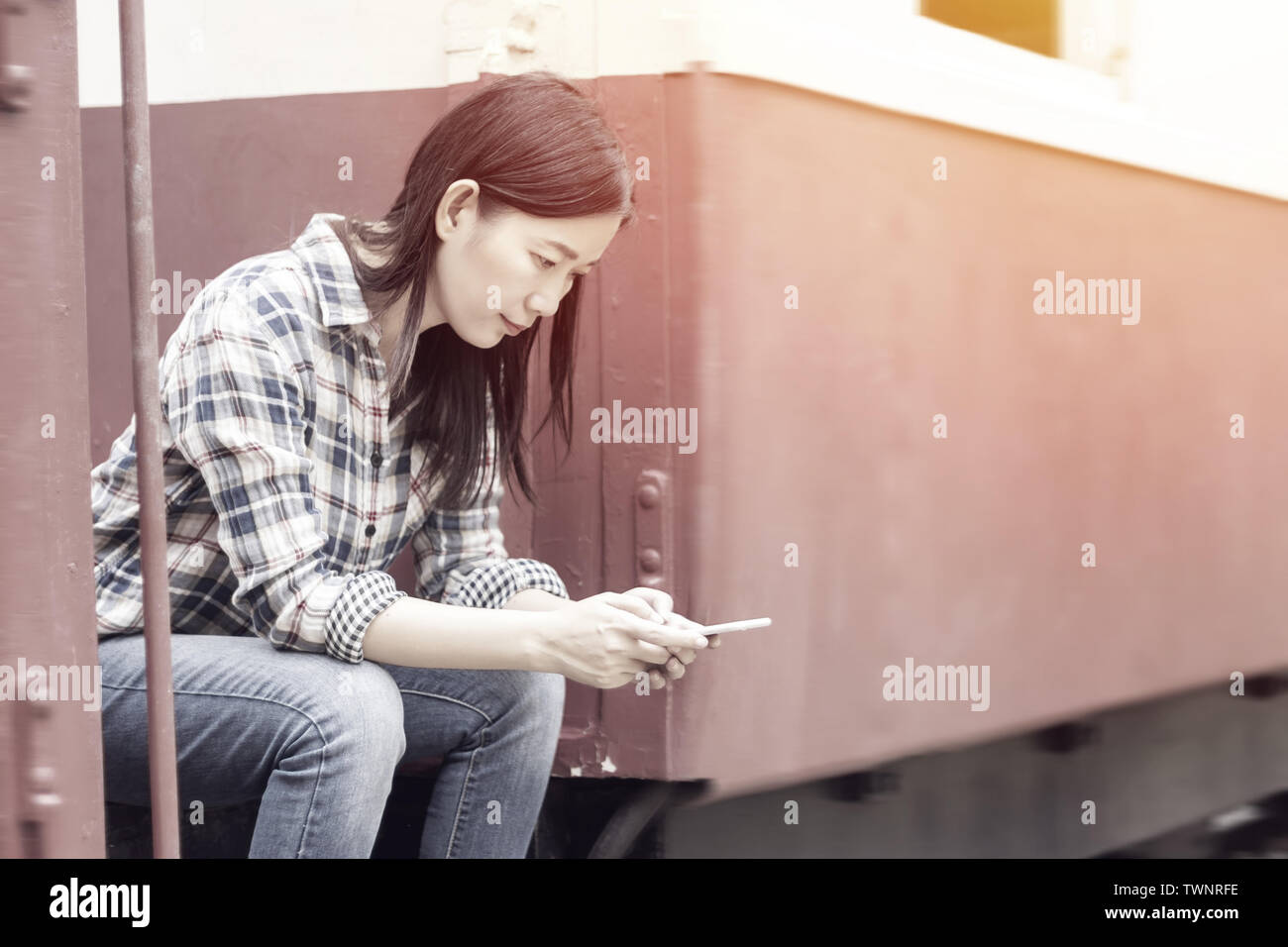 Asian woman using modern smartphone device on the train. female hands typing text message via mobile phone, social networking concept Stock Photo