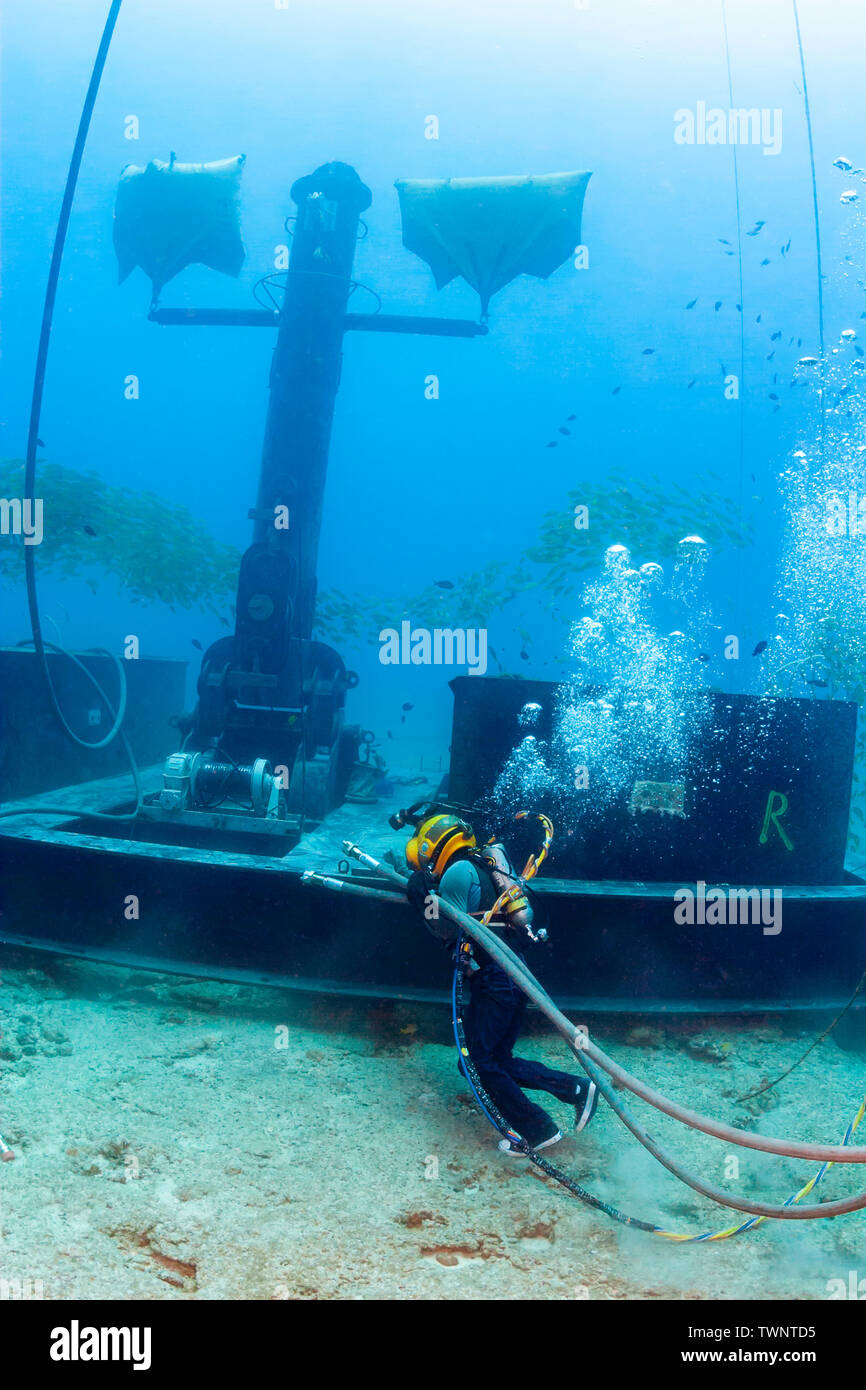 A commercial hard hat diver in Levi's and Converse All-Star running shoes  hauls hydraulic lines for a winch on the anchor device for a massive wave  en Stock Photo - Alamy
