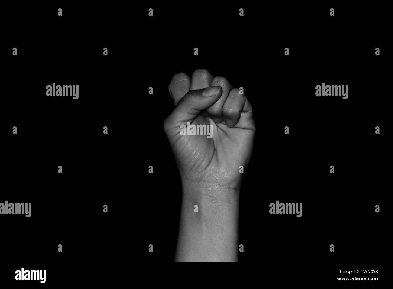 Isolated fist of woman on black background with palm facing towards camera. Showing concepts of female empowerment, revolution and strike. Stock Photo