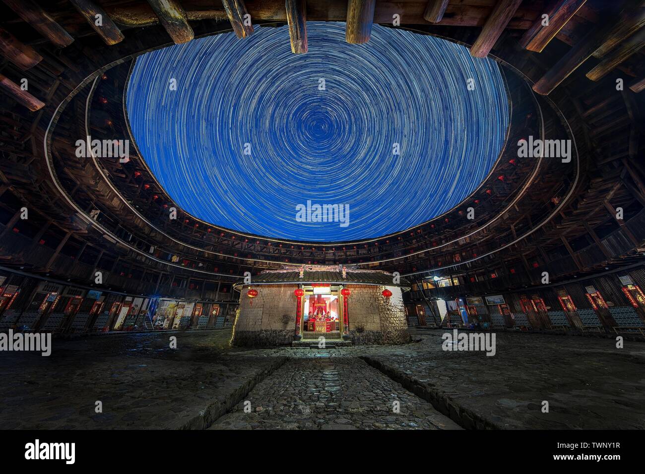 June 20, 2019, Fujian, China: The stars spin about during a long time exposure of the Fujian Hakka Tulou,  a unique mountain dwelling building in Fujian province, China. It is known as the ''Oriental ancient castle'' and the ''world architectural wonder''. Circular Tulou is a model residence for Hakka people. The Tulou buildings have become the most attractive tourist attraction in the region and are listed as a world cultural heritage site, attracting more and more foreign tourists. (Credit Image: © SIPA Asia via ZUMA Wire) Stock Photo