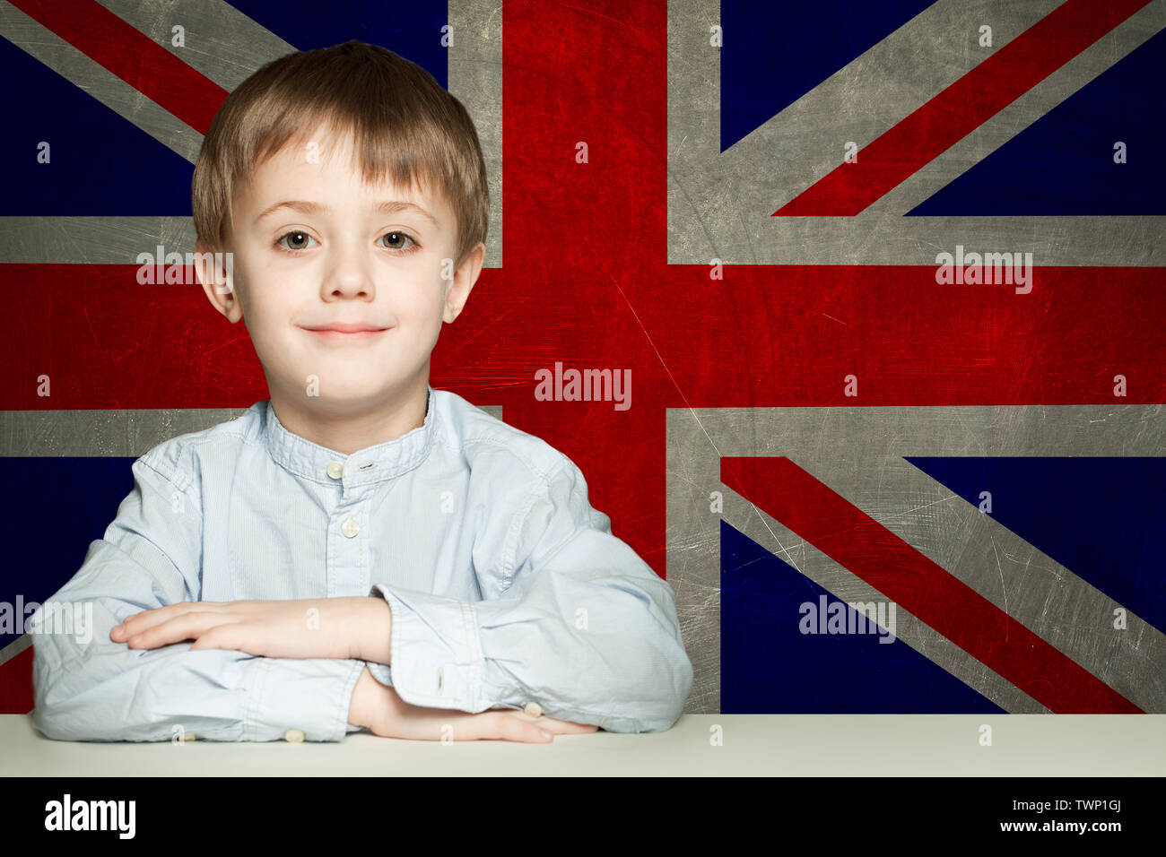 Happy child boy student in classroom against the UK flag background. Learn English concept Stock