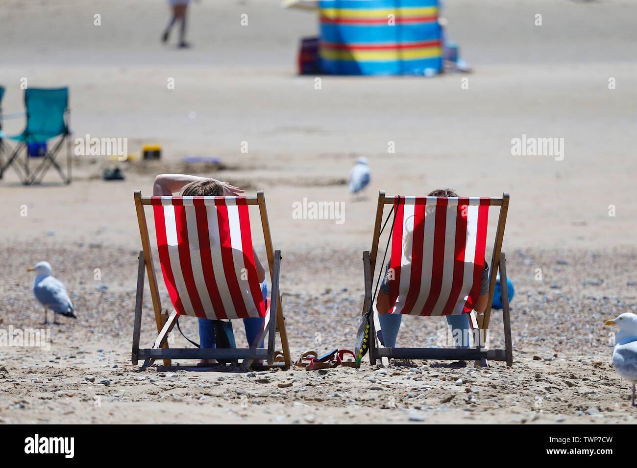 Camber, East Sussex, UK. 22 Jun, 2019. A beautiful sunny start to the weekend in Camber, East Sussex as people arrive to the Camber Sands beach to enjoy the warm weather. Couple sitting in silhouette on stripey deckchairs on the beach. ©Paul Lawrenson 2019, Photo Credit: Paul Lawrenson/Alamy Live News Stock Photo