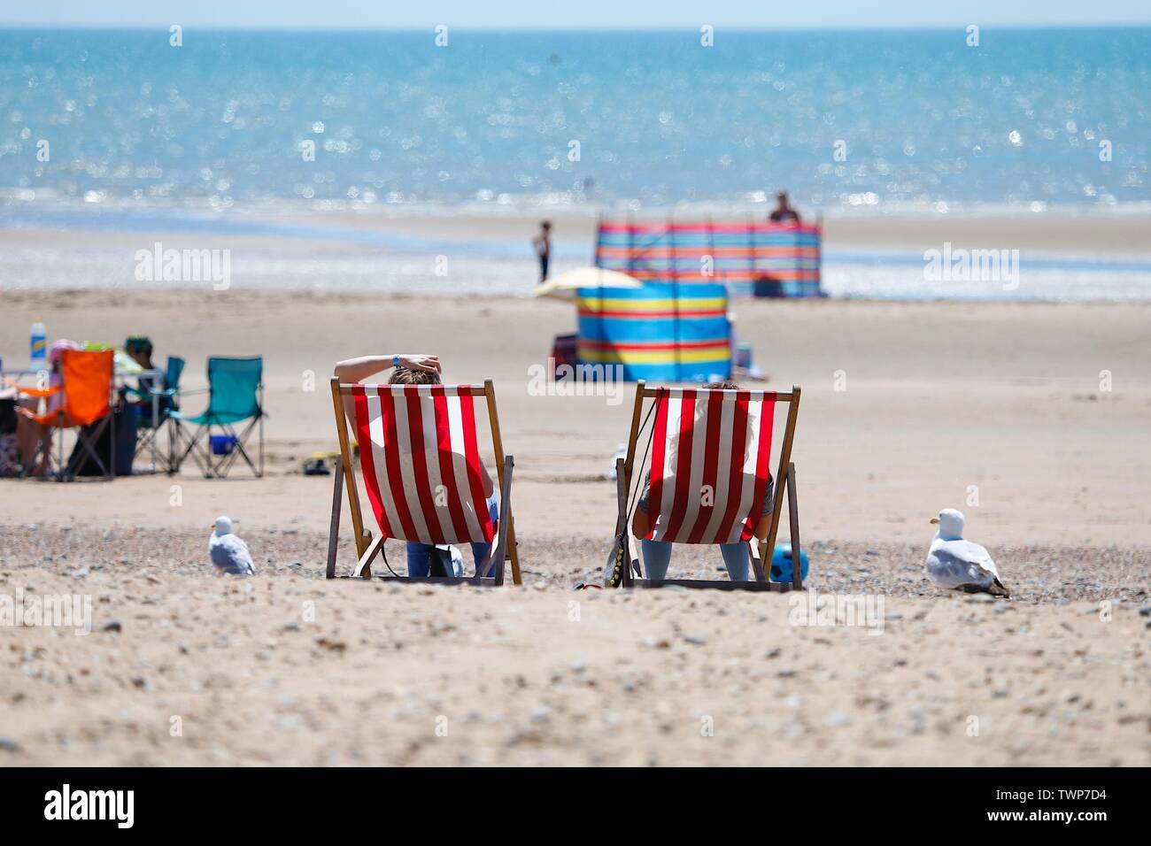 Camber, East Sussex, UK. 22 Jun, 2019. A beautiful sunny start to the weekend in Camber, East Sussex as people arrive to the Camber Sands beach to enjoy the warm weather. Couple sitting in silhouette on stripey deck chairs on the beach. ©Paul Lawrenson 2019, Photo Credit: Paul Lawrenson/Alamy Live News Stock Photo