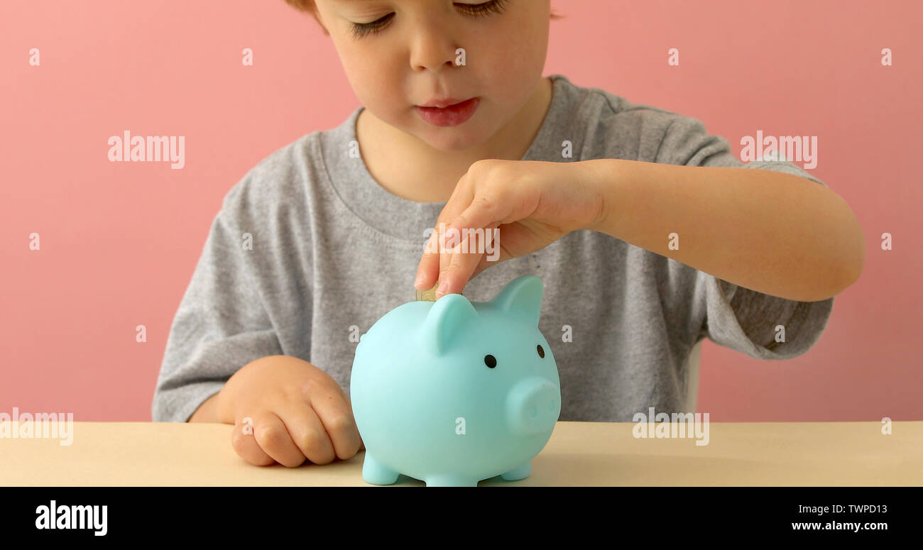 Little boy putting coins in a piggy bank Stock Photo
