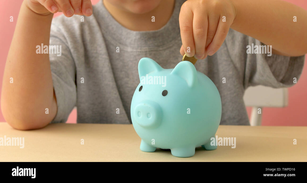 Little boy putting coins in a piggy bank Stock Photo