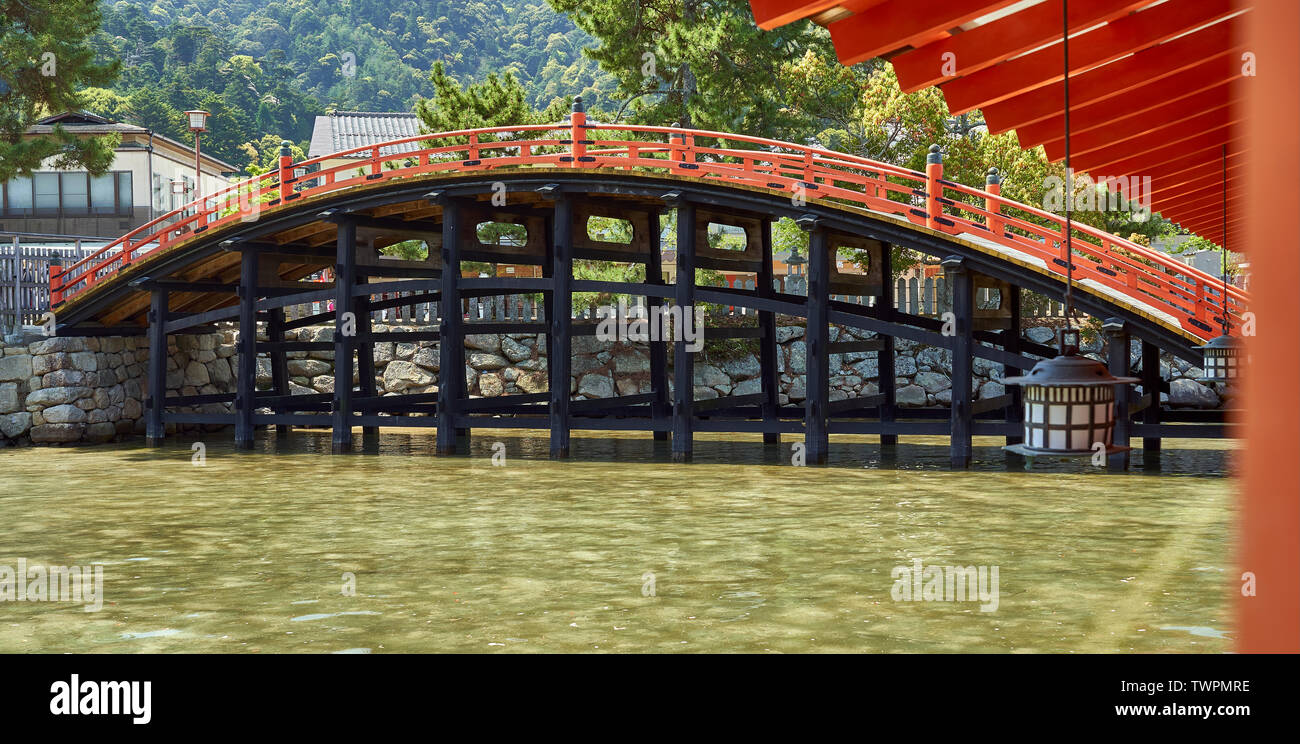 An orange and blacke colored bridge at the Itsukushima shrine. Stock Photo