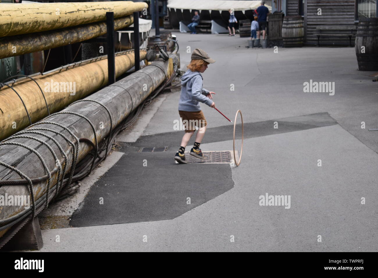 Boy playing stick and hoop at the SS Great Britain museum, Bristol, England Stock Photo